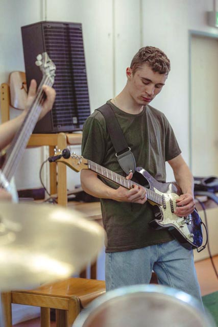 Musiker spielt Gitarre im Proberaum des Complete Music Camp
